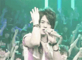 a man singing into a microphone with his hands in the air
