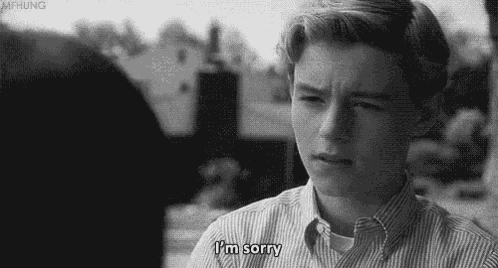 a young man in a striped shirt is saying i 'm sorry .