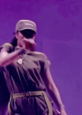a woman wearing a hat is singing into a microphone on stage .