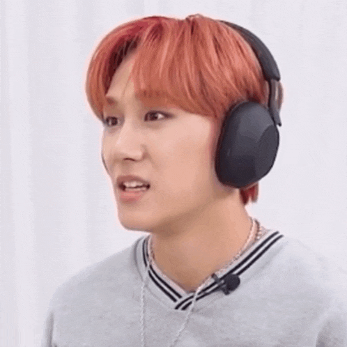 a man with red hair is wearing headphones and making a surprised face .