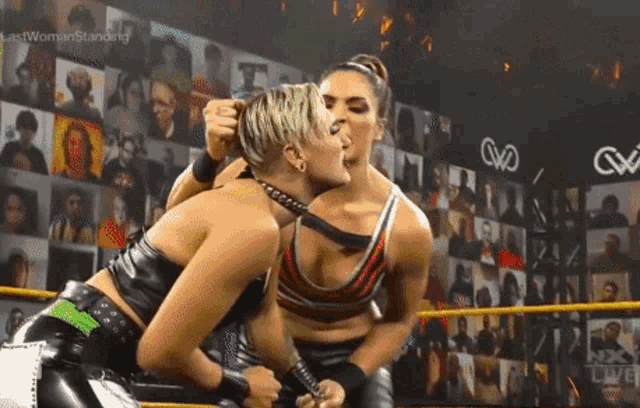 two women are wrestling in a ring and one of them is wearing a choker around her neck .