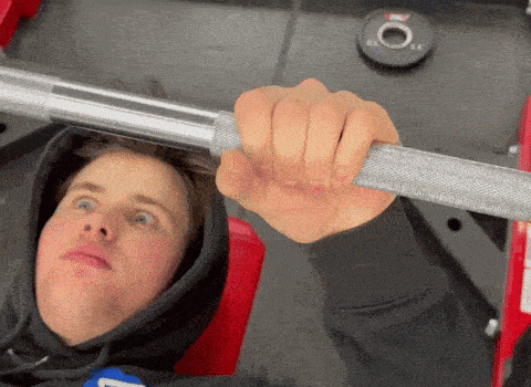 a man in a black hoodie is holding a barbell with the letter l on it