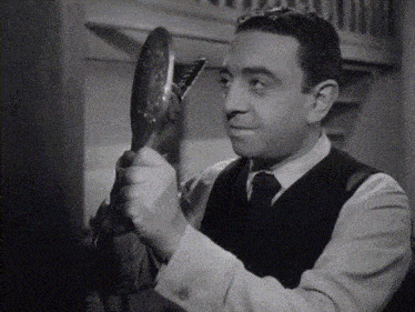 a man looks at himself in a mirror while wearing a vest