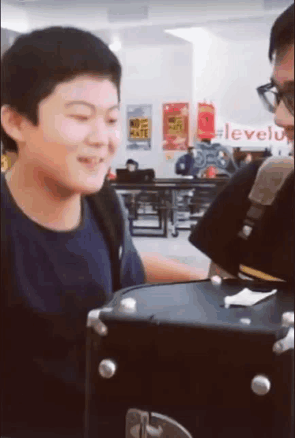 a boy in a blue shirt is smiling in front of a sign that says levelup