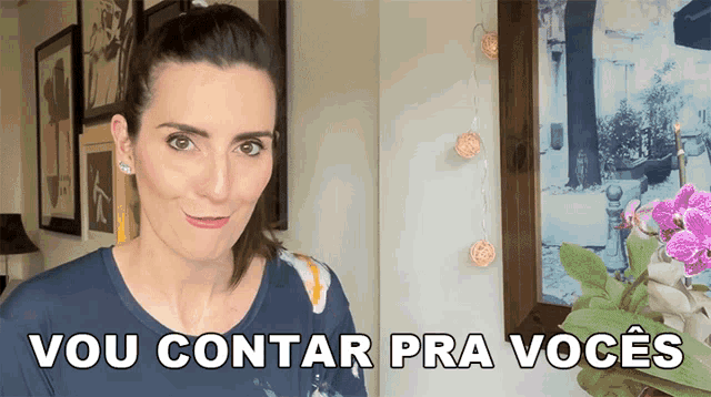 a woman in a blue shirt says vou contar pra voces in front of a framed picture