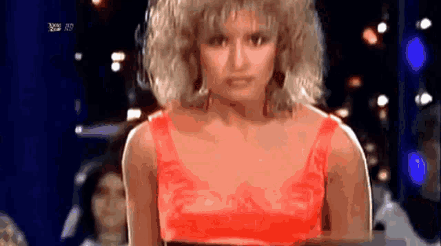 a woman in a red top is standing in front of a tv screen that says ' rtl hd ' on it