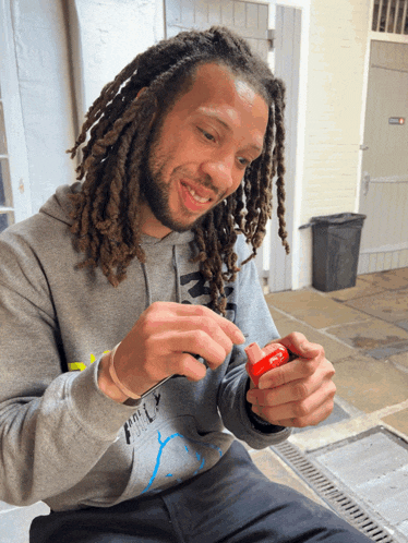 a man with dreadlocks wearing a grey hoodie that says ' ncl ' on it