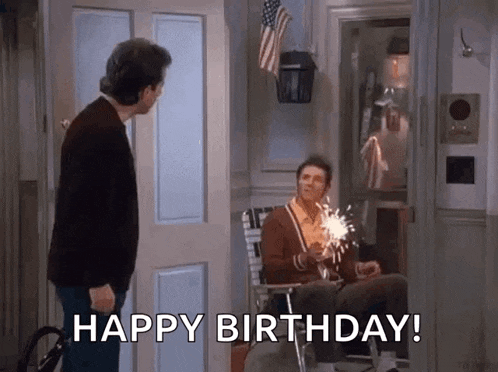 two men are standing next to each other in a room and one of them is holding a sparkler .