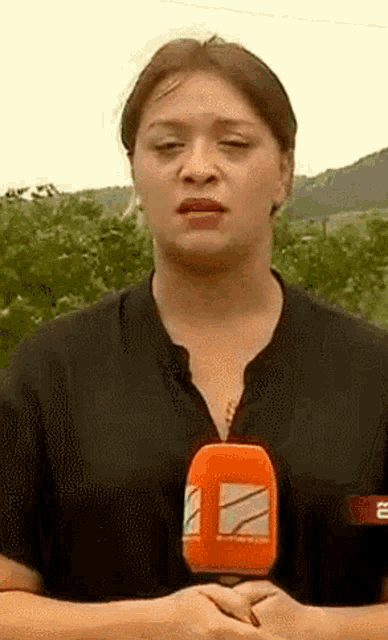 a woman in a black shirt is holding an orange microphone with the letter a on it .