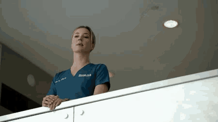 a woman wearing a scrub top that says design.ca stands on a balcony