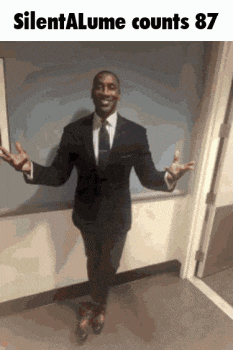 a man in a suit and tie is standing in a hallway with his arms outstretched .