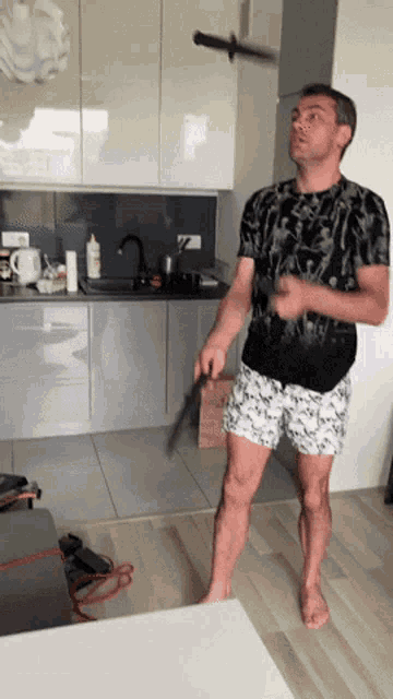 a man in a black shirt and white shorts is standing in front of a kitchen