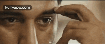 a close up of a man 's face with a hand on his eyebrow .