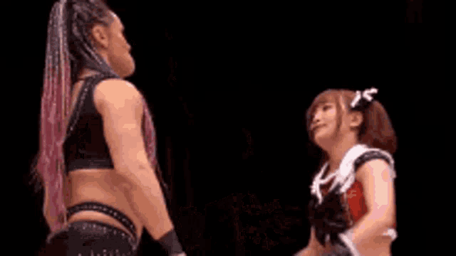 a woman is wrestling another woman in a ring while a referee looks on .