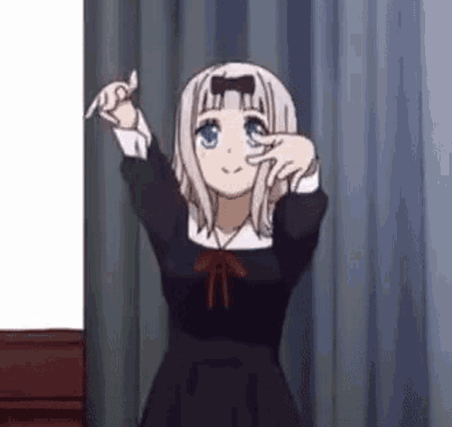 a girl in a black dress is standing in front of a white board and making a funny face .