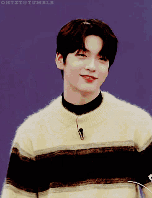 a young man in a yellow and black striped sweater smiles