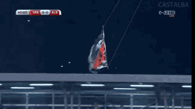 a black and red flag is hanging from a rope on a tv screen