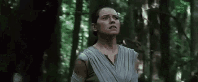 a woman is standing in the middle of a forest with her eyes closed .