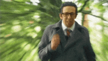 a man in a suit and tie is running in the park