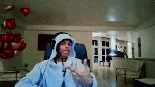 a man wearing a hoodie and headphones is sitting in a chair in a living room
