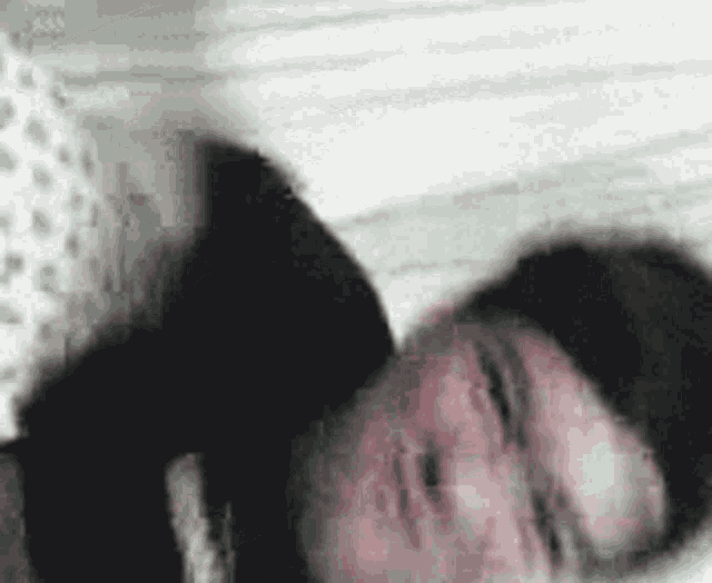 a blurry picture of a person laying on a bed with their head on another person 's shoulder .