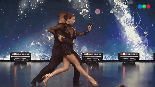 a man and a woman are dancing on a stage in front of a screen that says ' abc '