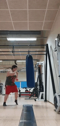 a man is boxing in a gym with a blue punching bag hanging from the ceiling