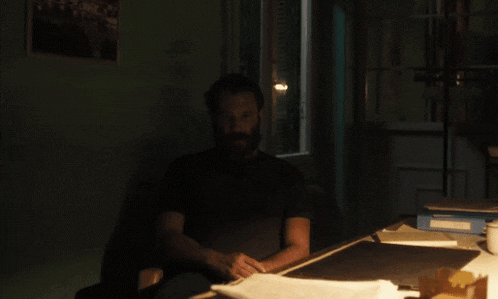 a man with a beard sits at a desk with papers on it