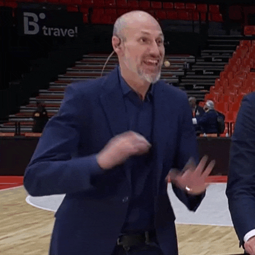 a bald man in a suit is standing on a basketball court .