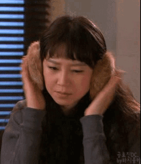 a woman wearing a pair of furry ear warmers looks down