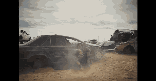 a man is sitting in a pile of junked cars