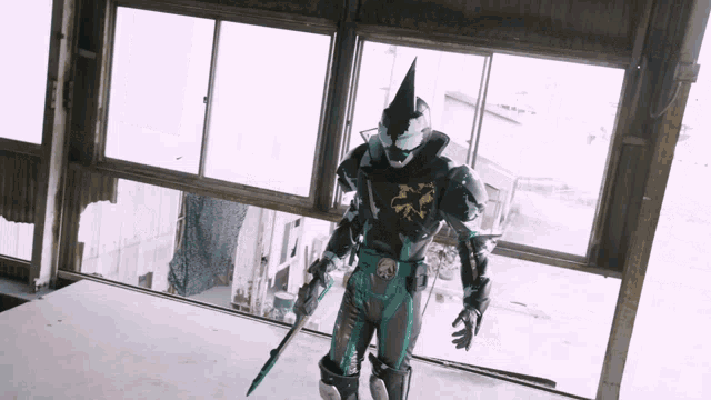a man in a superhero costume is standing in front of a window holding a sword