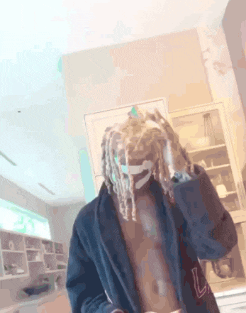 a man with dreadlocks is wearing a blue robe and a mask .