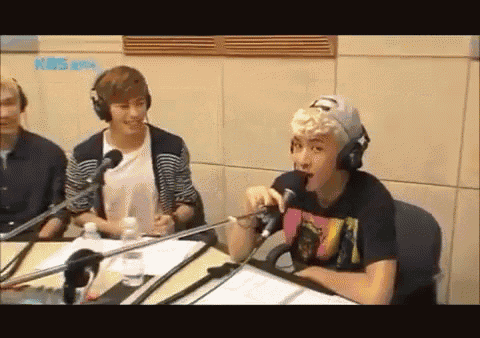a man wearing headphones is speaking into a microphone in front of a wall that says kbs