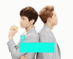 two young men are standing back to back and one is holding a lemon .