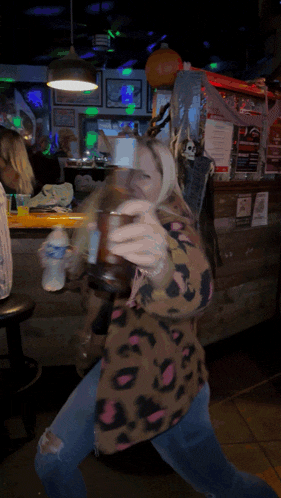 a woman in a leopard print shirt is holding a bottle of coke