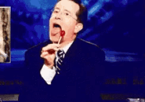 a man in a suit and tie is eating something with his mouth open