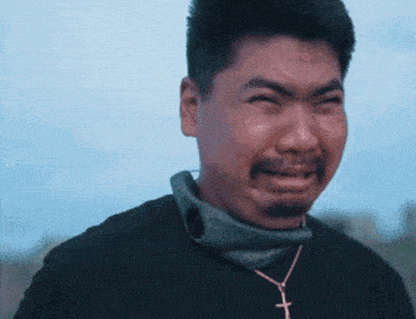 a man with a beard is crying and wearing a cross necklace