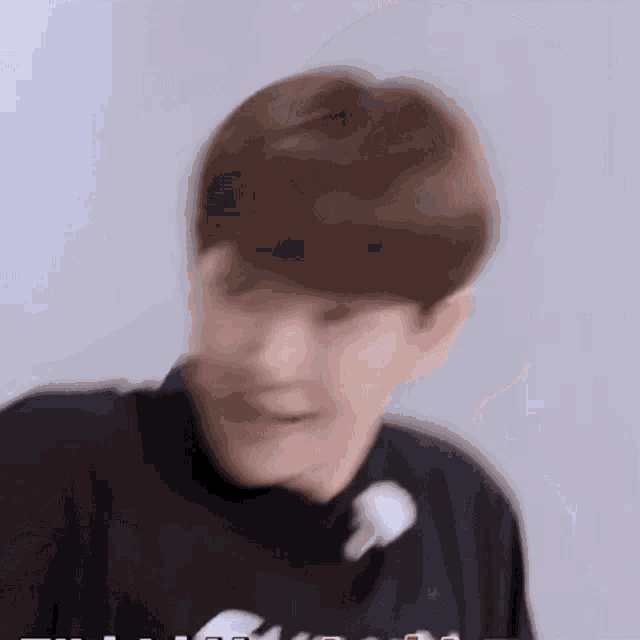 a blurry picture of a young man wearing a black shirt with a flower in his hair .