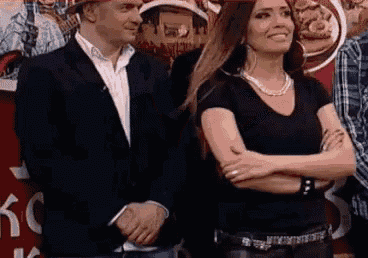 a man and woman are standing next to each other with their arms crossed and smiling .