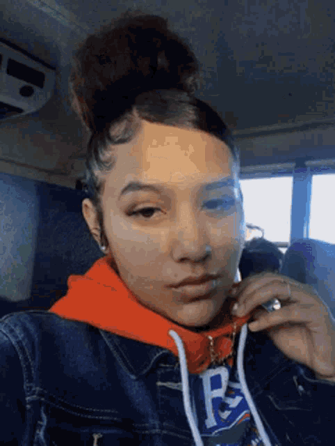 a girl wearing a hoodie with the letter b on it is taking a selfie
