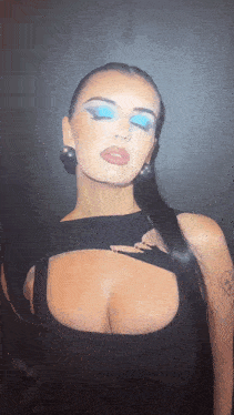 a woman in a black dress with blue eyeshadow and earrings