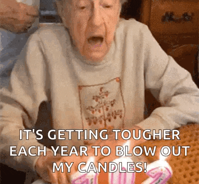 an elderly woman is blowing out her birthday candles