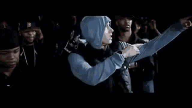 a group of people are standing in a dark room and one of them is wearing a hoodie