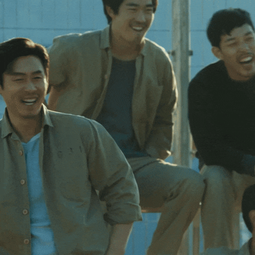 a man in a tan shirt with buttons on the sleeves is smiling