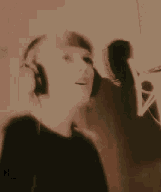a woman wearing headphones is singing into a microphone in a room .