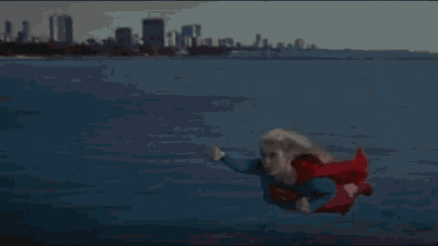 a little boy in a superman costume is flying through the air .