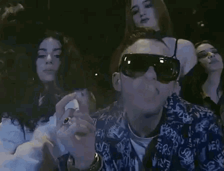 a man smoking a cigarette in front of a group of women and the words epic win !!!