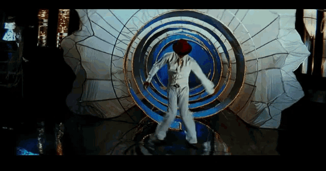 a man in a red hat is dancing in front of a blue and white circular object