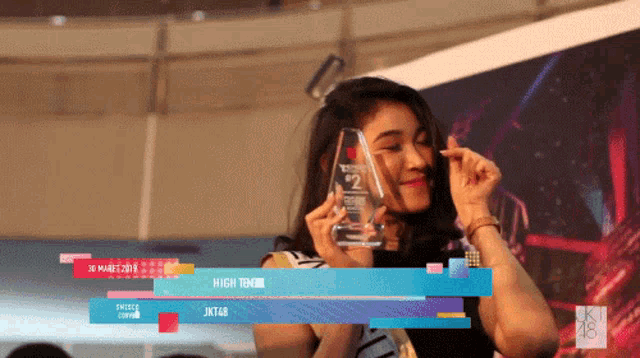 a woman is holding a trophy with the number 2 on it